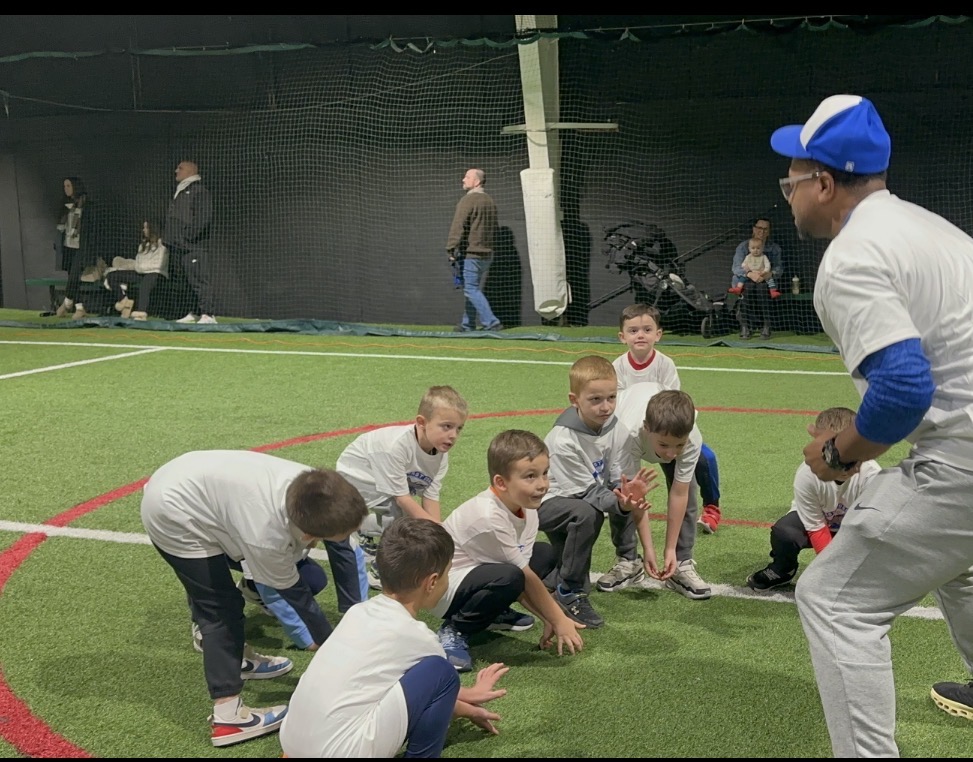 Coach leading a youth baseball clinic on the indoor turf